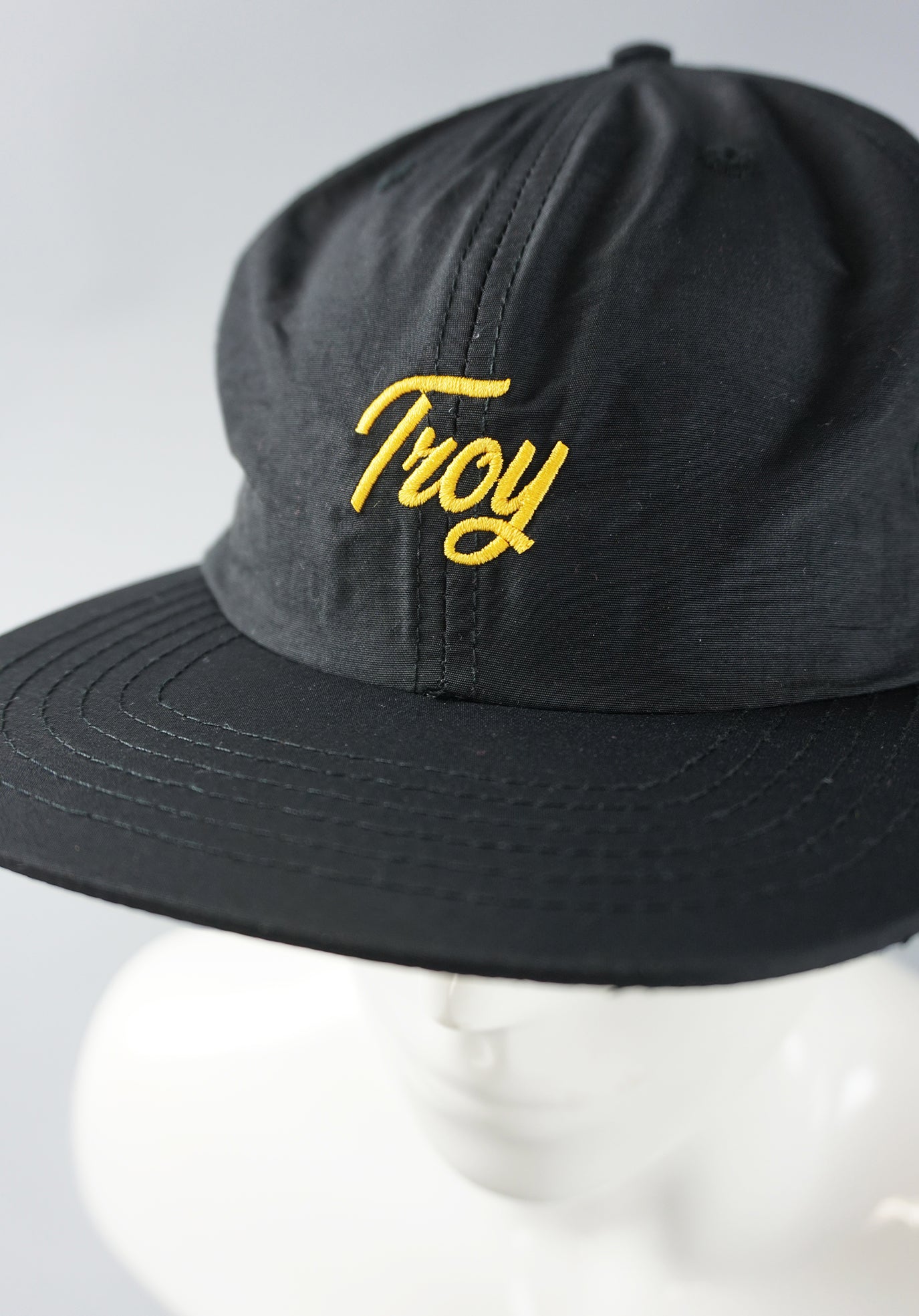 Close up of Troy script cap and gold embroidery.