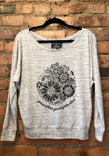 Image of the "Grow Where You're Planted" longsleeve. Drapey garment with a botanical/floral illustration printed on the front in black.